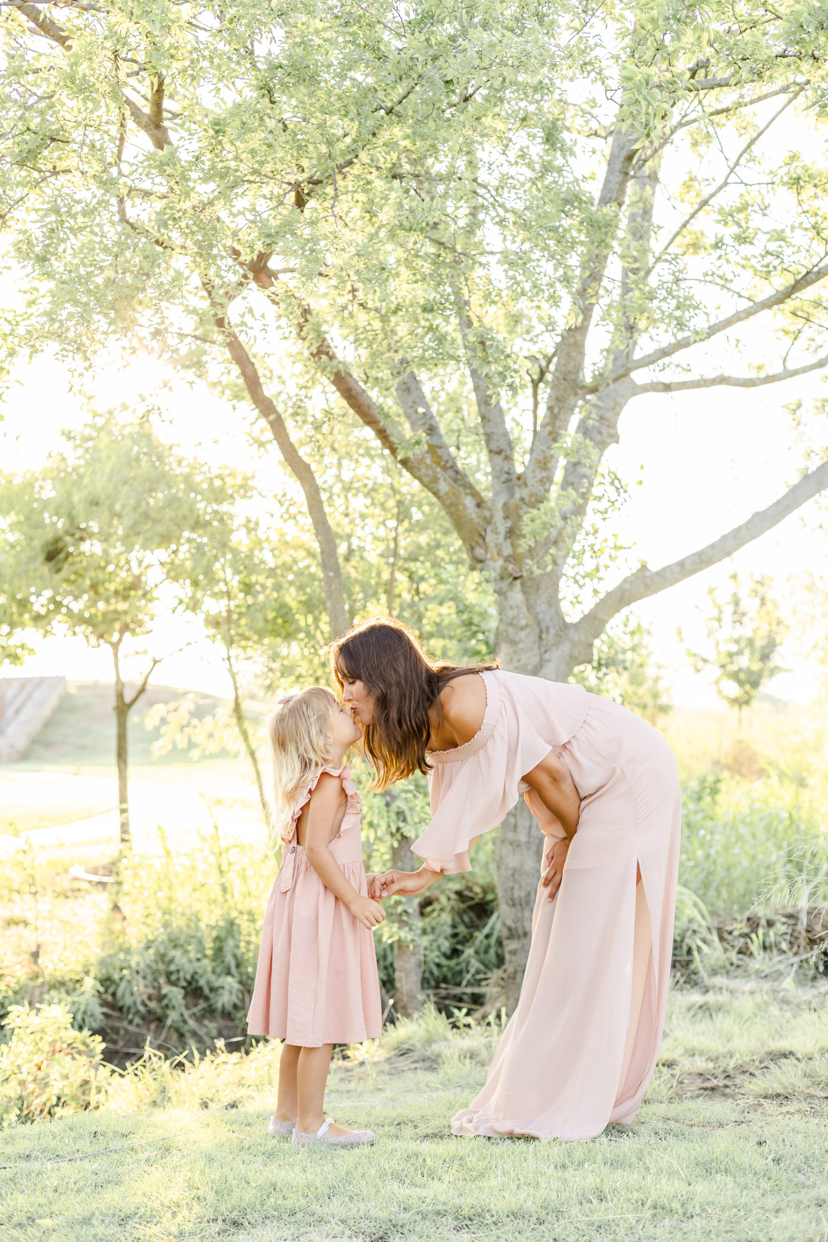 mom kisses daughter during a mommy and me sunrise session in celina texas with motherhood photographer ling waters photography